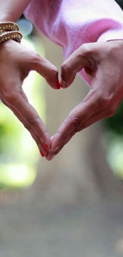 Hands forming a heart in soft pink and green nature background.