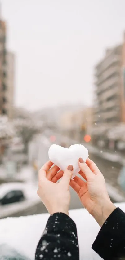 Person holding a snow heart in cityscape.