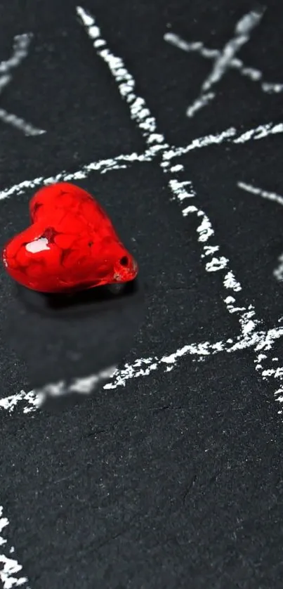 Red heart on black chalkboard with tic-tac-toe design.