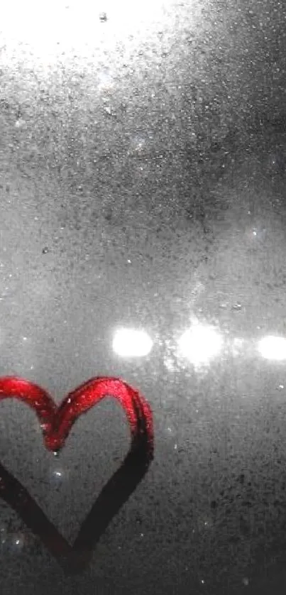 Red heart drawn on a frosty window with blurred lights in the background.