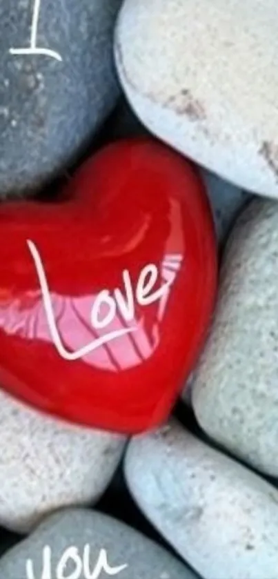Red heart on smooth gray rocks, symbolizing love.