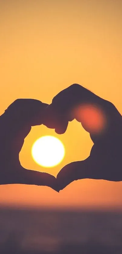 Silhouette of hands forming a heart around a vibrant sunset.