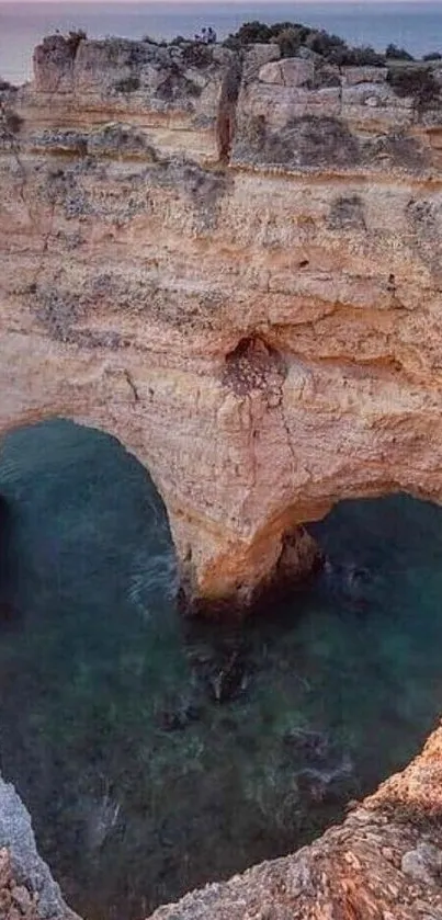 Heart-shaped coastal rock arch at sunset over ocean.