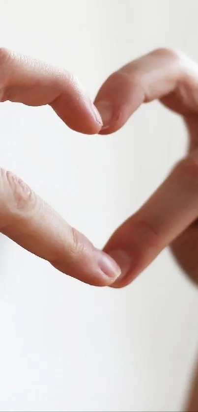 Hands forming a heart-shaped gesture on a light background.