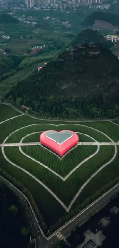 Aerial view of heart-shaped landscape in lush greenery with mountain backdrop.