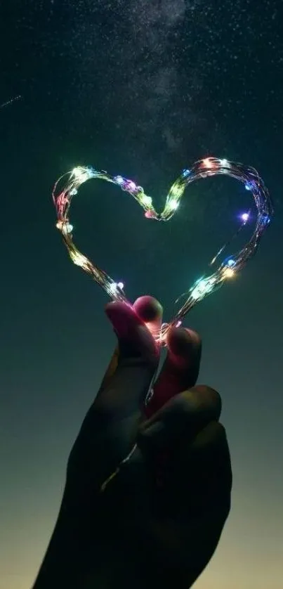 Heart-shaped light art against a dark starry sky, held by a hand.