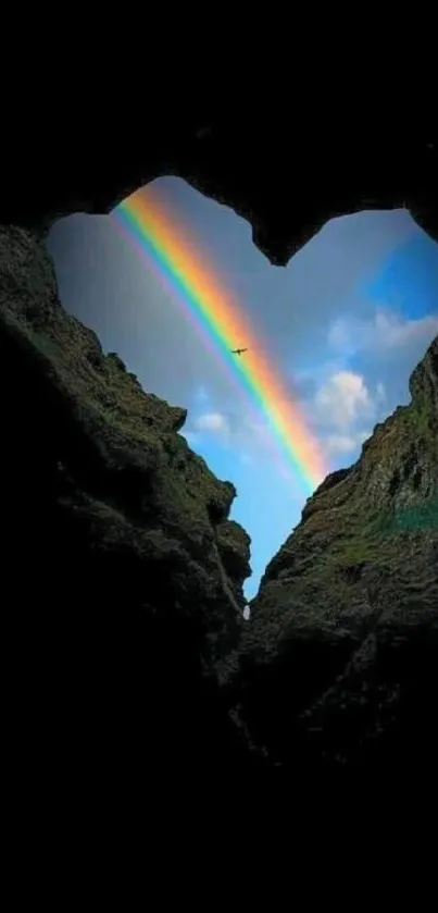 Heart-shaped cave with rainbow in sky.