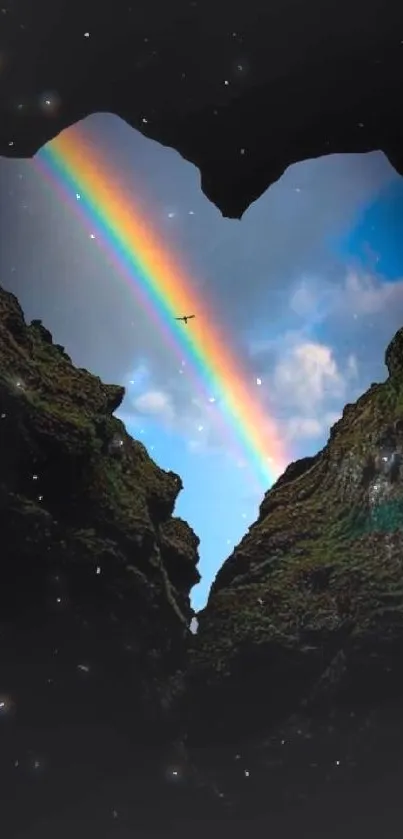 Heart-shaped silhouette framing a rainbow in the sky.