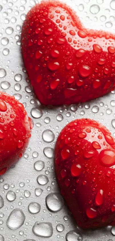 Four red heart shapes with droplets on a reflective surface.