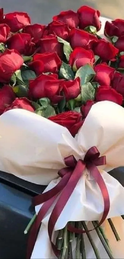 Heart-shaped bouquet of red roses with a large white bow.