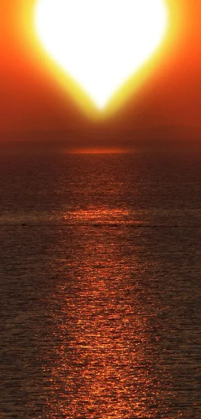 Heart-shaped sunset casting orange glow on ocean.