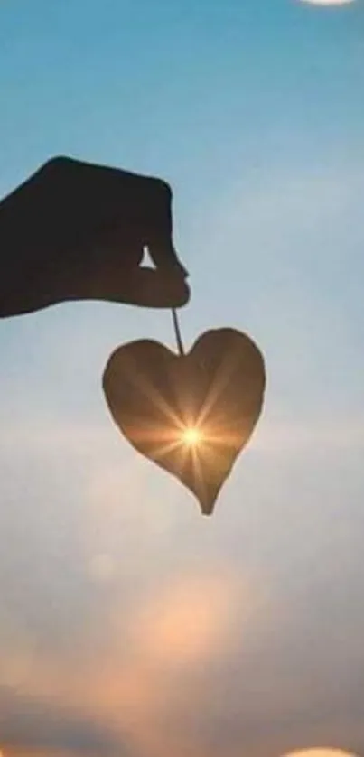 Silhouette of a hand holding a heart with sunset glow and bokeh sky.