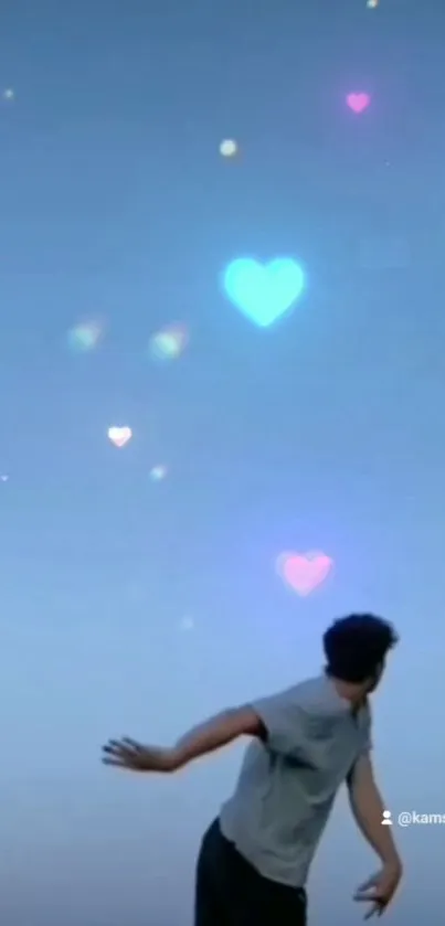 Man gazing at heart-shaped lights in blue sky wallpaper.