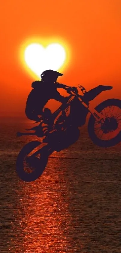 Motorbike silhouette against a heart-shaped sunset over the ocean.