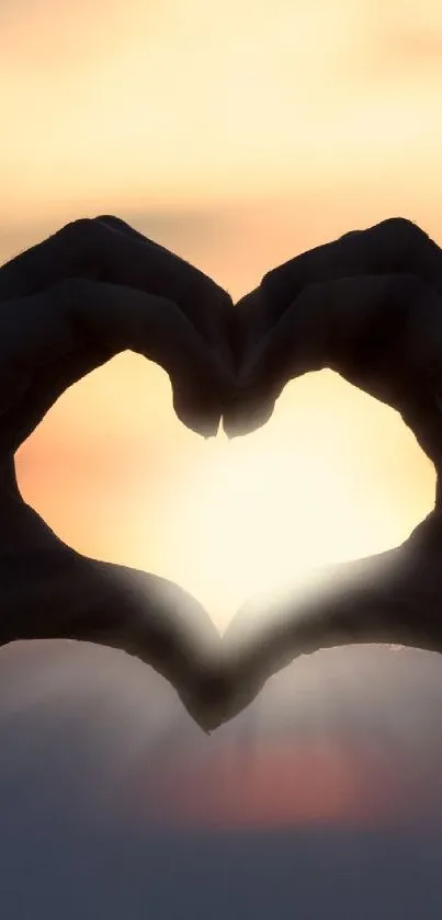 Hands form heart shape against glowing sunset.