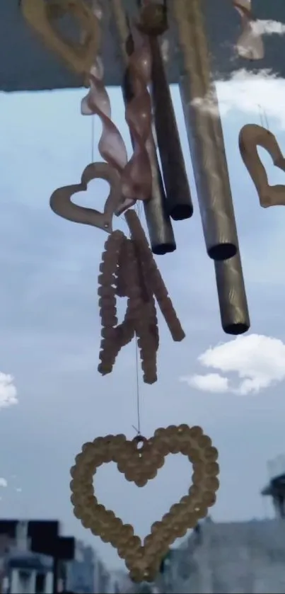 Heart-shaped chimes against a cloud-filled blue sky, with an urban landscape below.