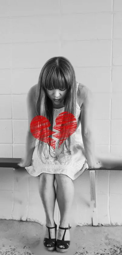 Girl sitting with red broken heart symbol on bench.