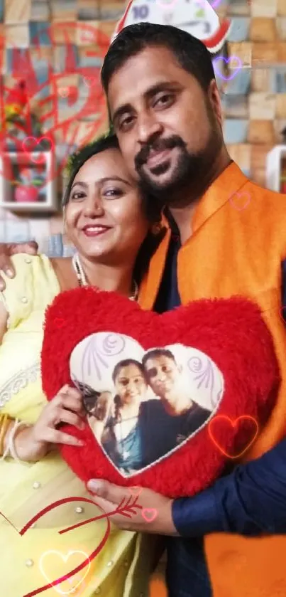 Smiling couple holding a heart-shaped cushion with their photo.