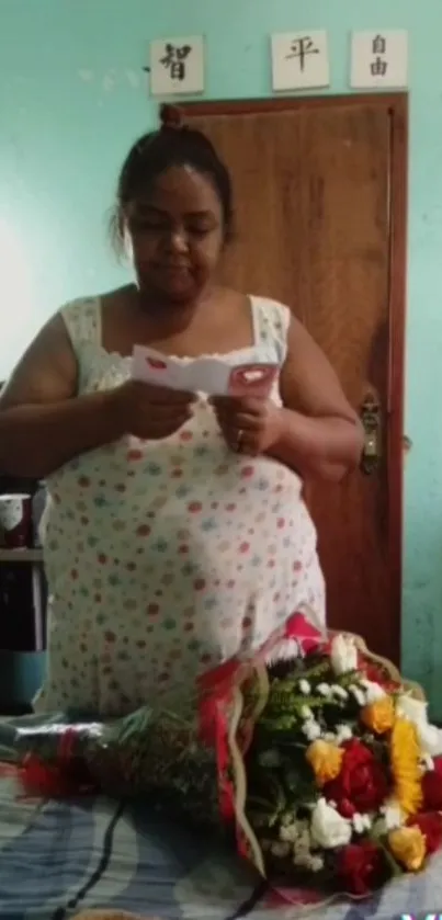 Woman reading a note beside a vibrant floral bouquet on bed.