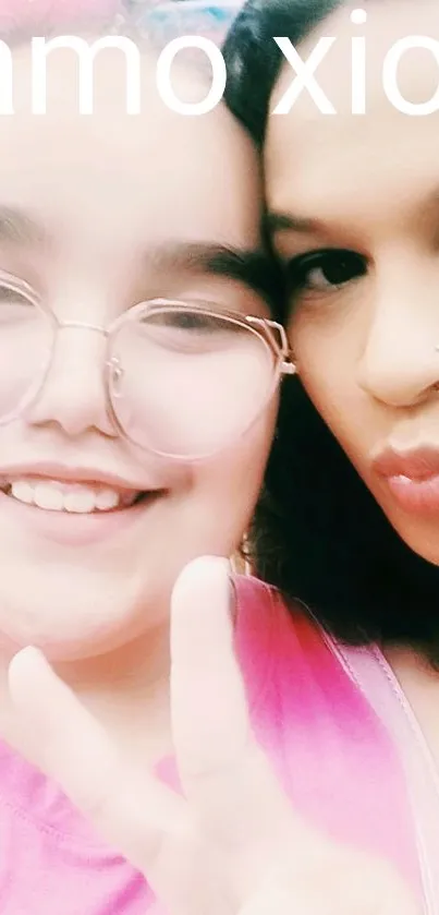 Two friends smiling and holding up a peace sign in a close-up selfie.