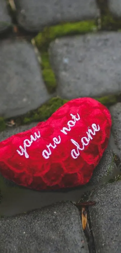 Red heart on cobblestones with 'You Are Not Alone' message.