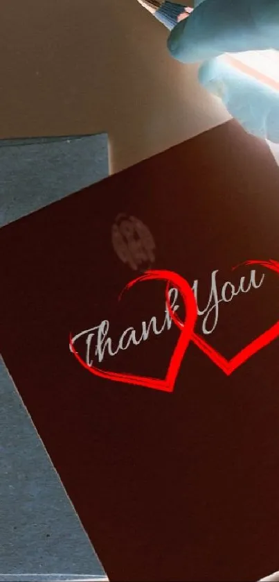 Wallpaper of a thank you note with red hearts on a dark brown background.