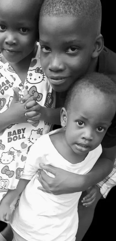 Black and white wallpaper of three smiling children.