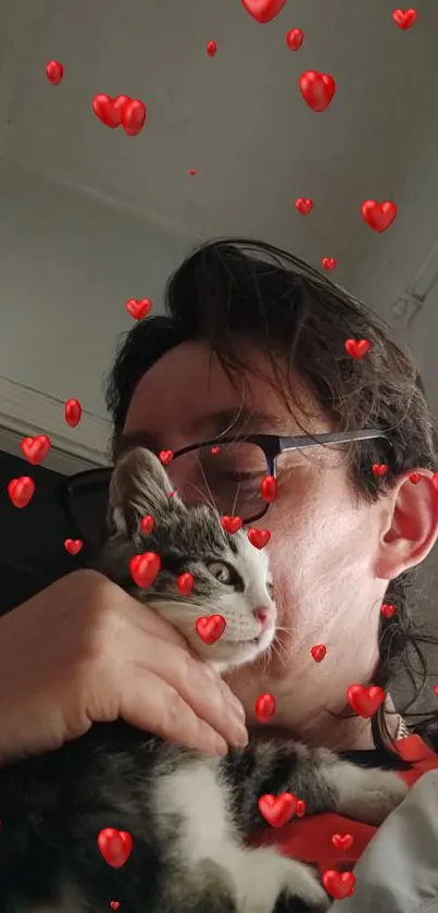 Person holding a kitten with red hearts in the air.