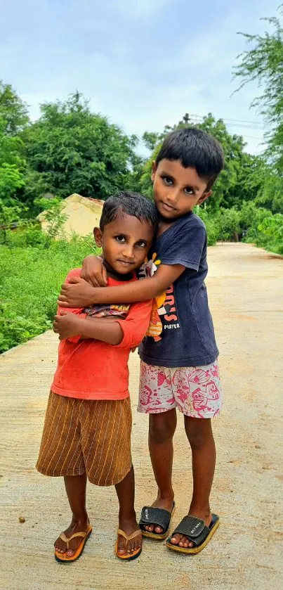 Two children hugging on a rural path with green surroundings.