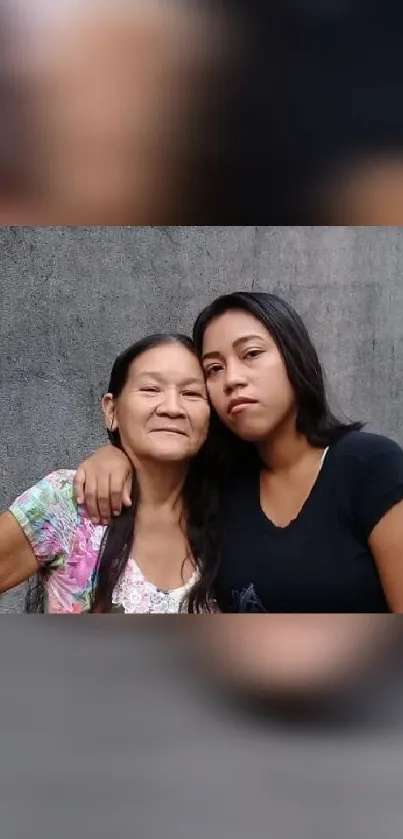 Mother and daughter embracing with gray background.