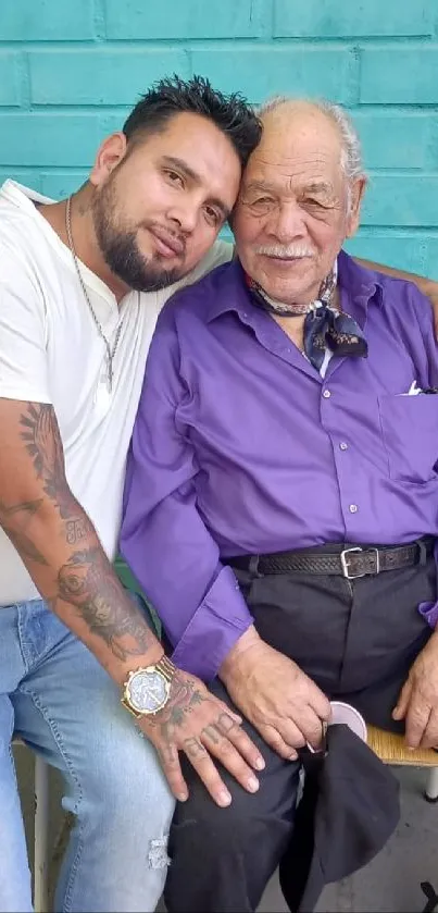 Father and son embracing against a teal wall.