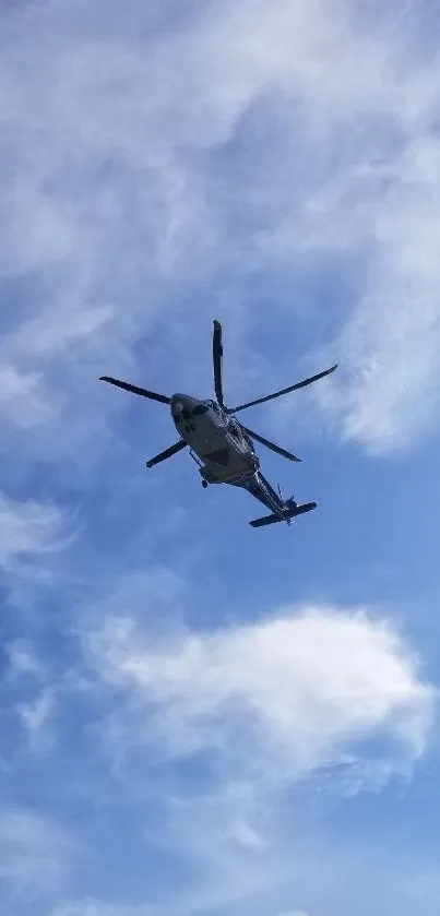 Helicopter against a bright blue sky with white clouds.