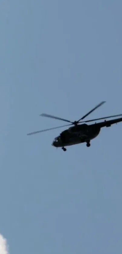 Silhouette of a helicopter flying in a blue sky.