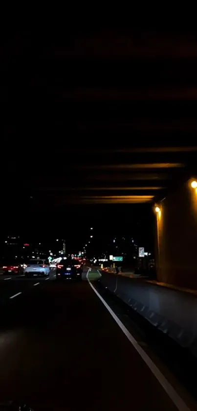 Highway at night with distant city lights under a dark sky wallpaper.