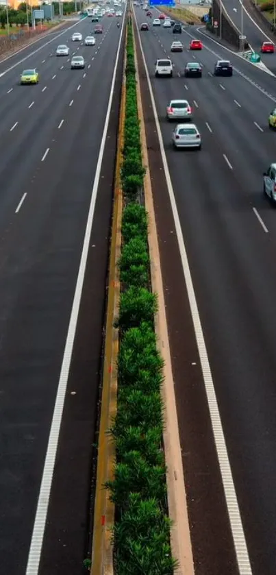 Aerial view of a bustling highway with cars and nature divider.