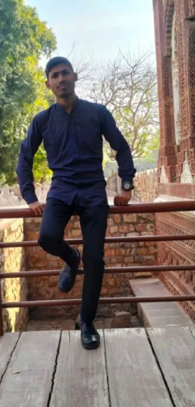 Man leaning on a railing with historic backdrop.