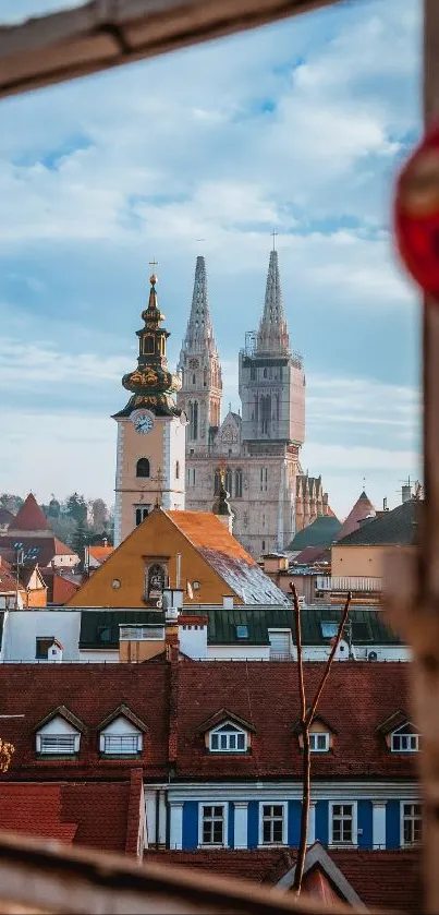 View of a historic cityscape through a window, featuring spires and colorful rooftops.