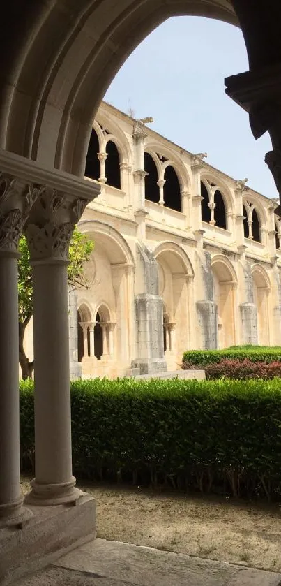 Historic stone cloister view under archway with lush garden.