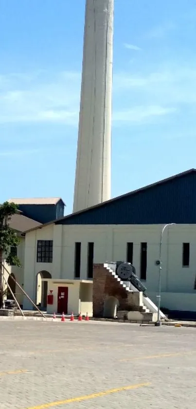 Industrial building with tall chimney under clear blue sky.