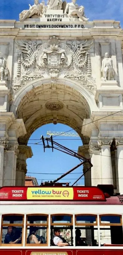 Red streetcar under Lisbon's iconic arch on a sunny day.