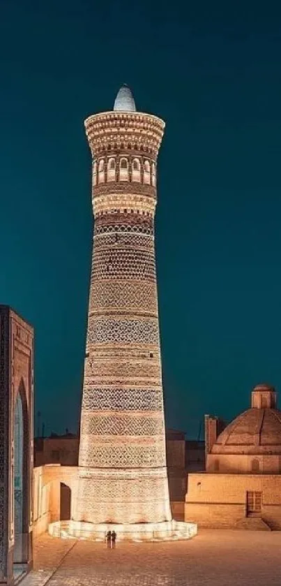 Illuminated historic minaret at night with ancient architecture.