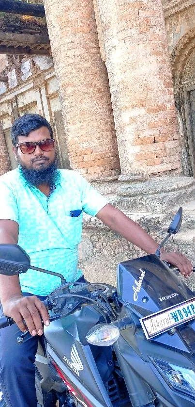 Motorcyclist in front of ancient brick ruins.