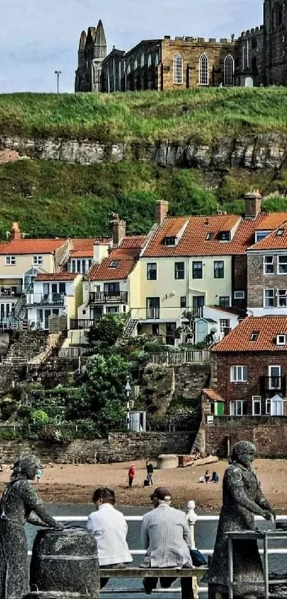 Seaside village with historic castle and red-roofed houses overlooking statues.