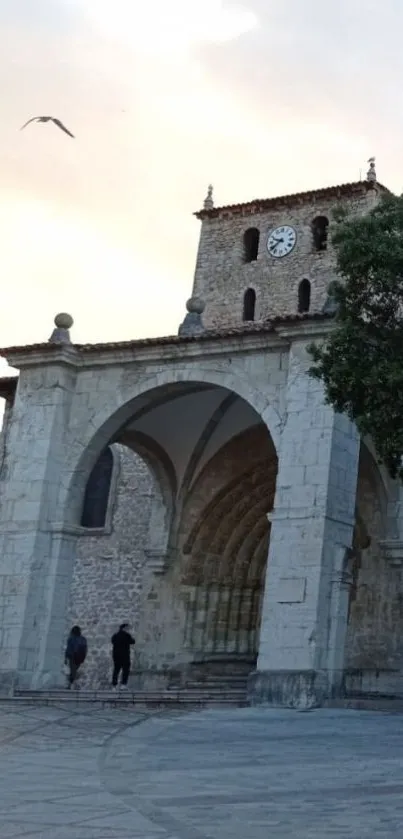 Historic stone archway with clock tower under a twilight sky.