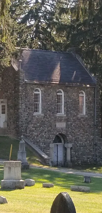 Historic stone chapel in a cemetery with lush greenery.