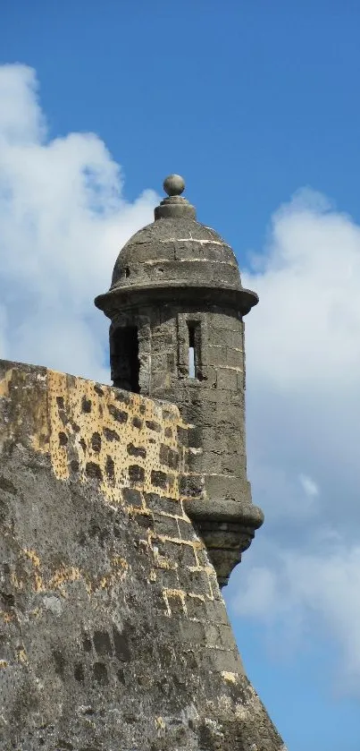 Ancient stone fort under a bright blue sky with clouds.