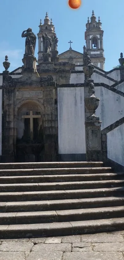 Historic stone staircase with elegant statues and a cross in the background.