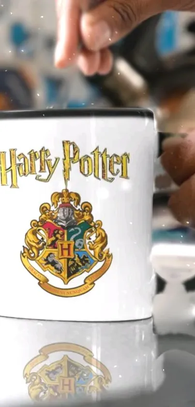 Harry Potter Hogwarts crest mug with hand on white background.