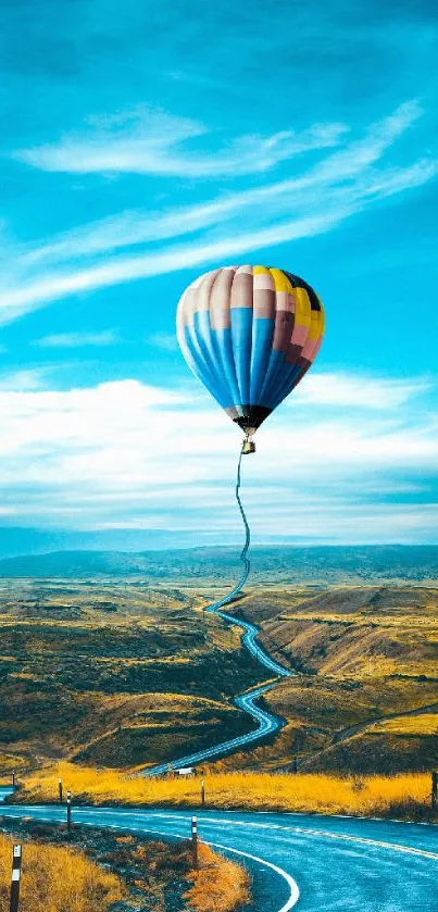 Colorful hot air balloon over a winding road with a bright blue sky.