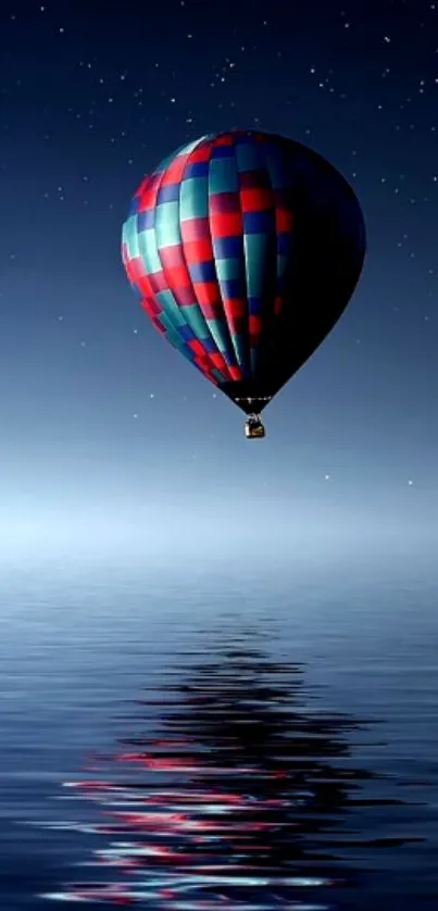 Hot air balloon floats over calm water under a starry night sky.